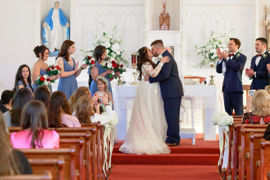 bride and groom sharing their first kiss at sacred heart chapel Fairhope, AL.