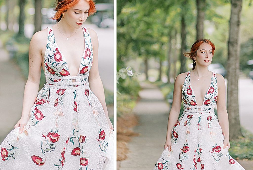 
A young  female College student outside serenbe enjoying a outdoor walk wearing a beautiful white long prom dress that has red and green flowers on it. 