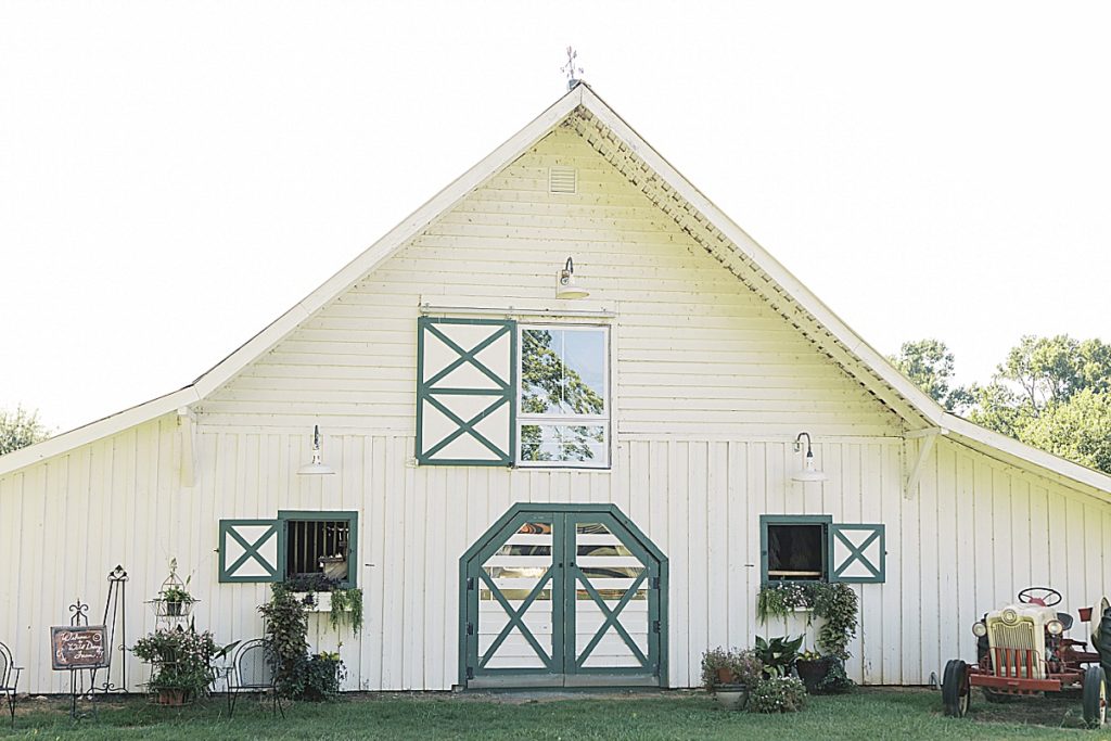 White Barn at Wild Daisy Farm with green trim and beautiful window flower beds. 